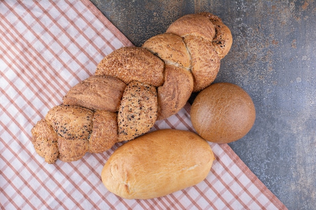 Assortment of bread loaves on a tablecloth on marble surface