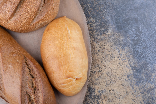 Assortment of bread types on a wooden board on marble surface