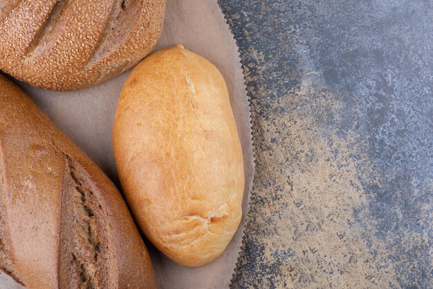 Assortment of bread types on a wooden board on marble surface