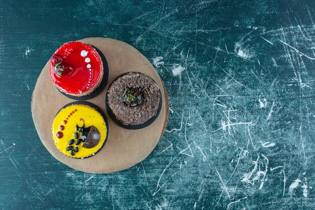 Assortment of cakes on a wooden board on blue.