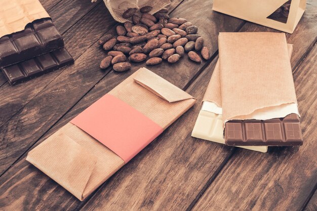 Assortment of chocolate bars and cocoa beans on wooden table