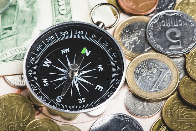 Assortment of coins and compass to travel