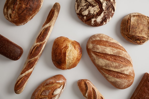 Assortment of different types of bread, loaf, baguettes, made of wheat, rye organic flour on leaven, isolated on white surface. Bakery and healthy food concept. Natural biologial products.