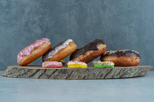 Assortimento di ciambelle su una tavola di legno su marmo.