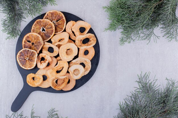 Assortment of dried apple and orange slices on a small tray on white background.