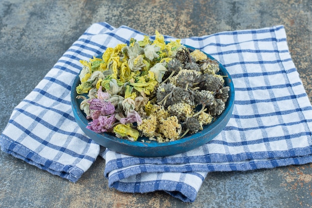 Assortment of dried organic flowers on blue plate.