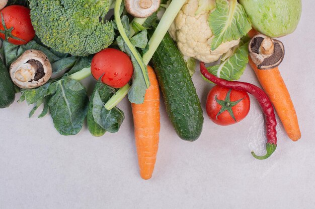 Assortment of fresh vegetables on white table.