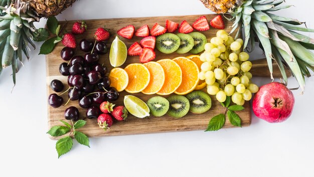 Assortment of fruits on chopping board over white background