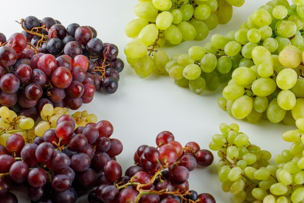 Assortment of grapes on white, high angle view.