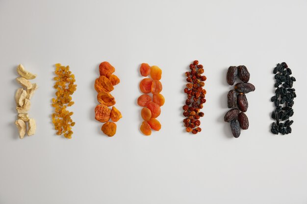 Assortment of highly nutritious dried fruits rich in vitamins and minerals. Dried apple, raisins, apricot, physalis, barberry and dates on white background. Healthy snack can be added to porridge