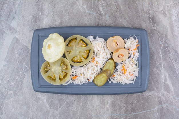 Assortment of homemade pickles on dark plate.