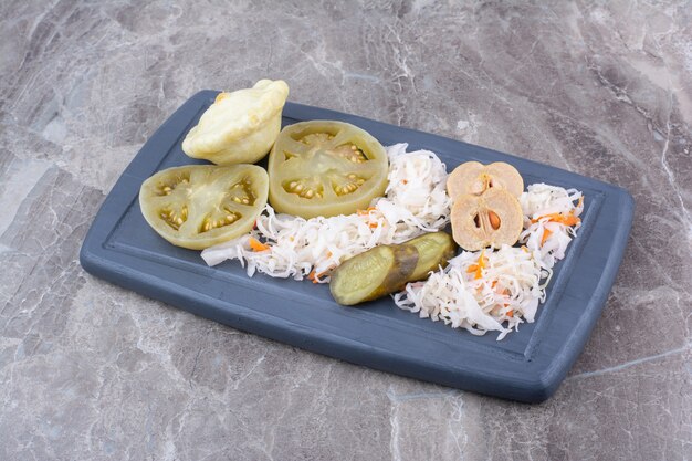 Assortment of homemade pickles on dark plate.