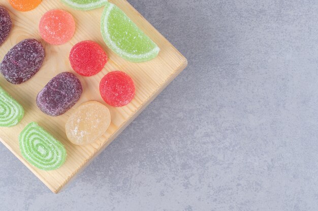 Assortment of marmelades on a wooden board on marble table.