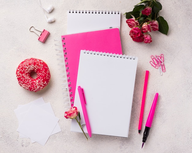 Assortment on notebooks with doughnut and bouquet of roses