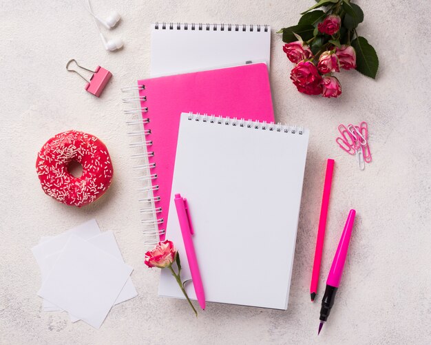 Assortment on notebooks with doughnut and bouquet of roses