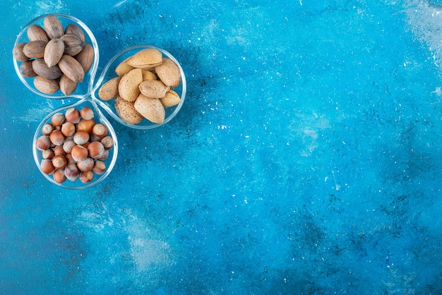 Assortment of nuts on a bowls on the blue surface