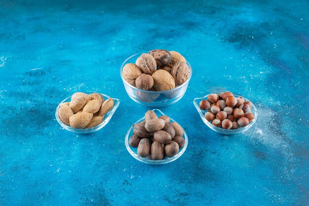 Assortment of nuts on a bowls on the blue surface