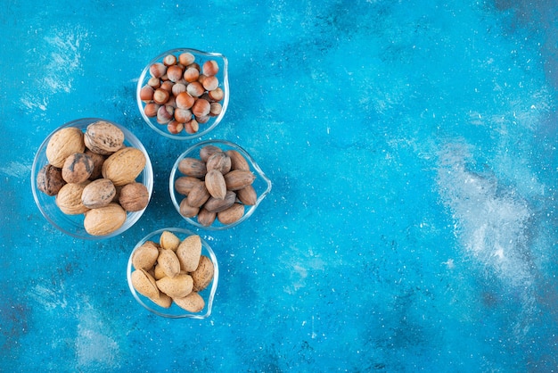 Assortimento di noci su ciotole, sul tavolo blu.