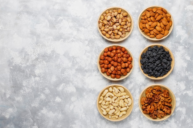 Assortment of nuts in ceramic plates. Cashew, hazelnuts, walnuts, pistachio, pecans, pine nuts, peanut, raisins.top view