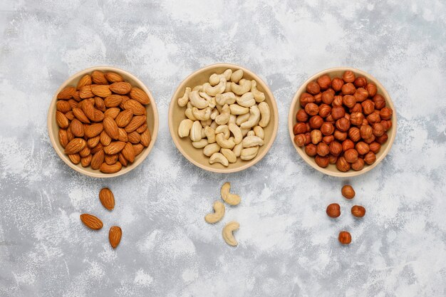 Assortment of nuts in ceramic plates. Cashew, hazelnuts, walnuts, pistachio, pecans, pine nuts, peanut, raisins.top view