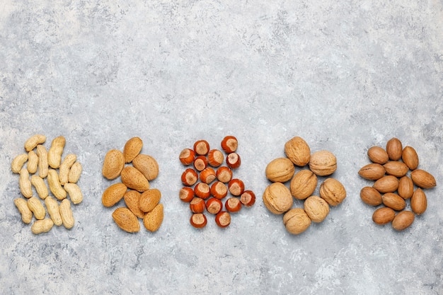 Ассортимент орехов на бетонной поверхности. Фундук, грецкие орехи, орехи пекан, арахис, миндаль, вид сверху