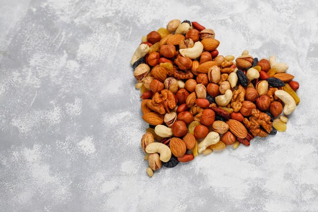 Assortment of nuts shape of heart Cashew, hazelnuts, walnuts, pistachio, pecans, pine nuts, peanut, raisins.top view