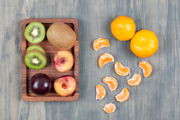 Бесплатное фото Ассортимент свежих фруктов на деревянной тарелке
