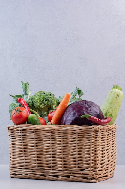 Assortment of organic vegetables in wooden basket.