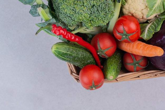 Assortment of organic vegetables in wooden basket.