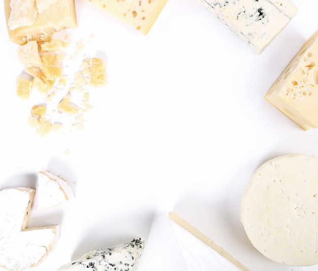 Assortment of pieces of cheese, top view, white copyspace background