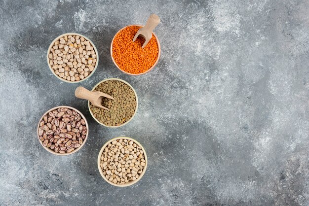 Assortment of raw dry legumes composition on marble table surface.