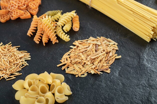 Assortment of raw pasta on dark.