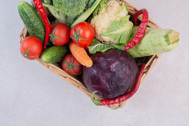 Assortment of raw vegetables in wooden basket.