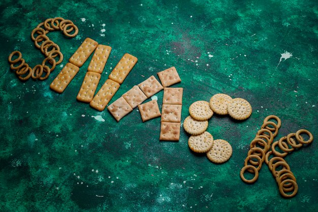 Assortment of salt crackers shot from the top on colorful with copy . Salty party snacks mix