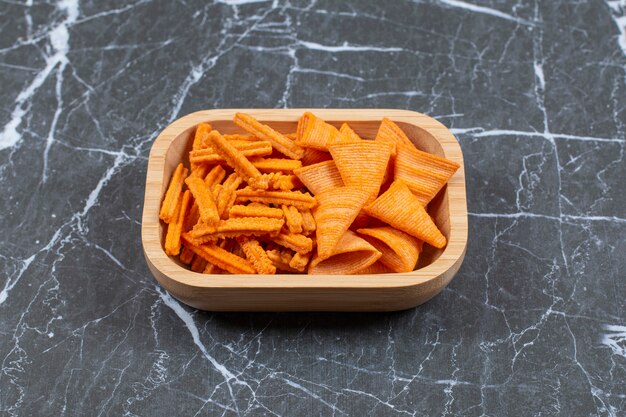 Assortment of spiced chips on wooden plate.
