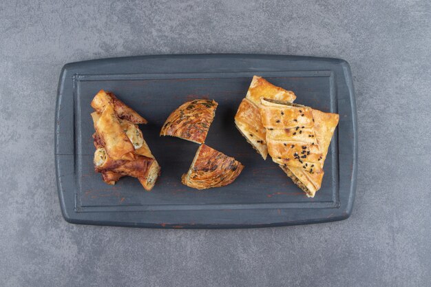 Assortment of stuffed pastries on dark board. 