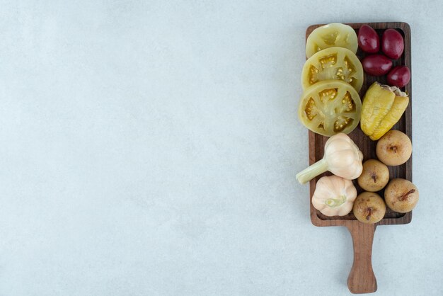 Assortment of tasty fermented vegetables on wooden board.