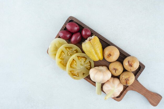 Assortment of tasty fermented vegetables on wooden board.