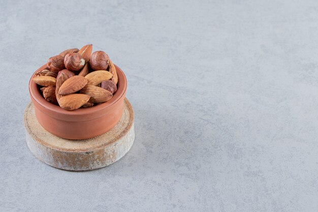 Assortment of tasty organic nuts in bowl on stone background.