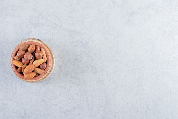 Assortment of tasty organic nuts in bowl on stone background.