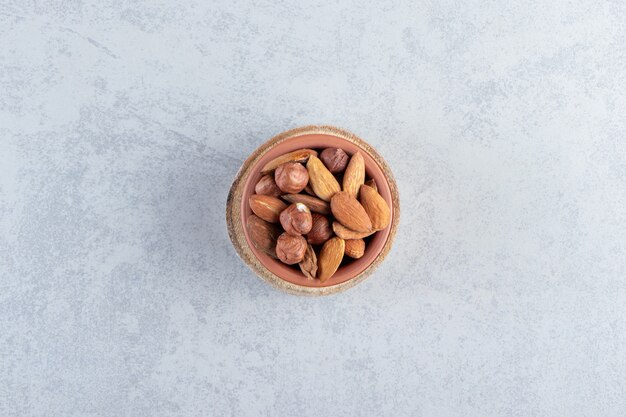 Assortment of tasty organic nuts in bowl on stone background.