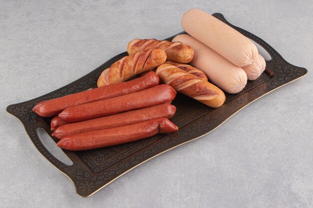 Assortment of tasty sausages on metal tray.