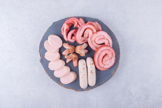 Assortment of tasty sausages on wood piece. 