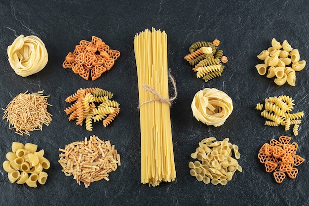 Assortment of uncooked pasta on black.