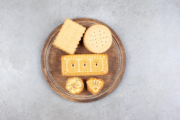 Ассортимент различного печенья на деревянной доске на мраморном фоне. Фото высокого качества