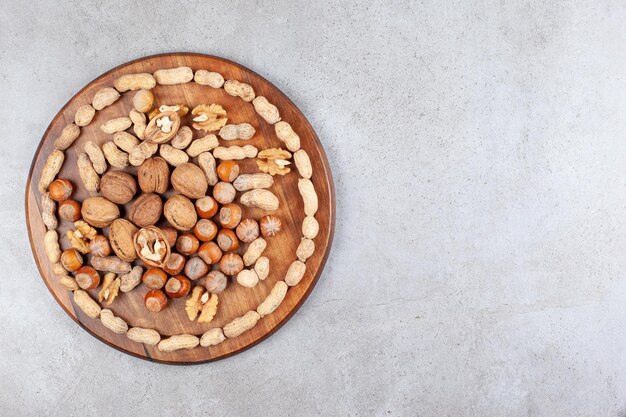 An assortment of various nut types on wooden board on marble background. High quality photo