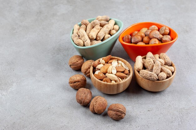 An assortment of various nut types in wooden bowls on marble background. High quality photo