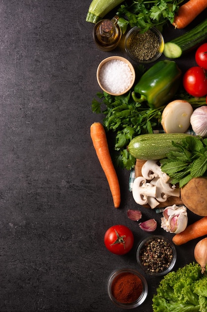 Assortment of vegetables herbs and spices on black background Top view Copy space