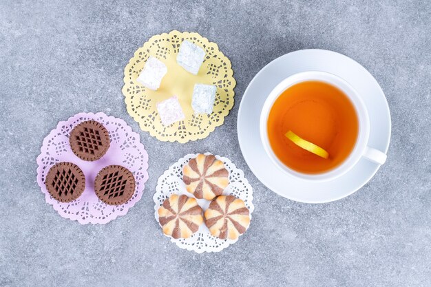 Assortments of sweets and cup of tea on marble surface