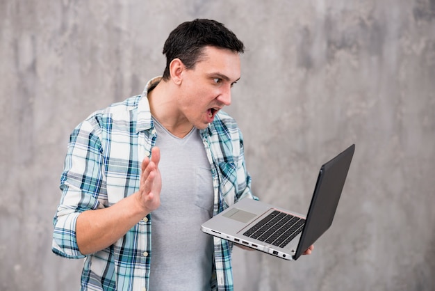 Foto gratuita ragazzo stupito con laptop e bocca aperta